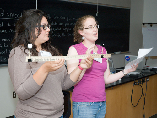 Two women demonstrating the yardstick eclipse activity