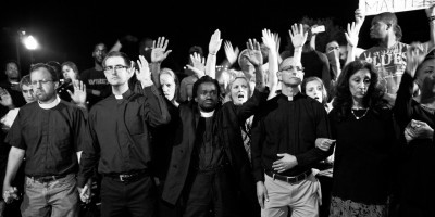Rev. Sekou and other clergy kneel at a protest
